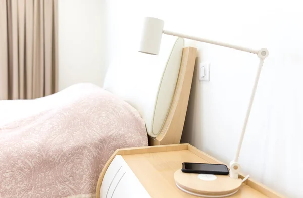 Kablosuz smartphone üzerinde yatak yakınındaki lamba şarj — Stok fotoğraf