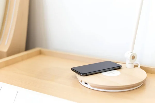 Wireless smartphone charging on lamp near bed — Stock Photo, Image