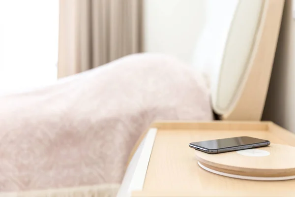 Ricarica smartphone wireless su lampada vicino al letto — Foto Stock