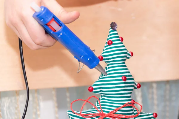 Girl using glue to decorate Christmas tree. Handmade present