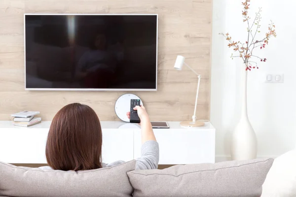 Mujer joven viendo la televisión en la habitación —  Fotos de Stock