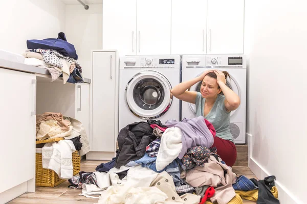 Sad woman sitting in a laundry room — Stock Photo, Image