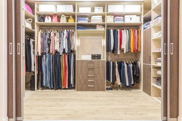 Armario moderno de madera con ropa colgando en el carril en el walk in closet — Foto de Stock