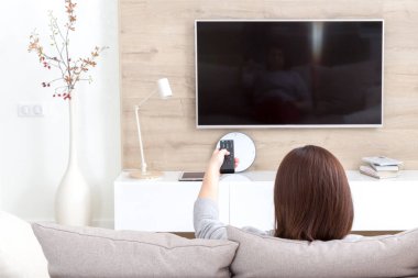 Odada televizyon izleyen genç bir kadın.