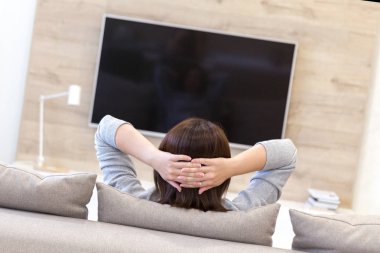 Odada televizyon izleyen genç bir kadın.