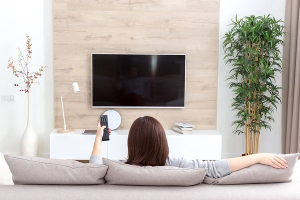 Mujer joven viendo la televisión en la habitación —  Fotos de Stock