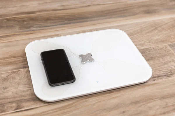 Smart scale standing on floor connected by bluetooth to smartphone