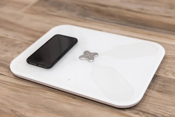 Smart scale standing on floor connected by bluetooth to smartphone