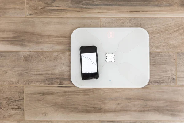 Smart scale standing on floor connected by bluetooth to smartphone