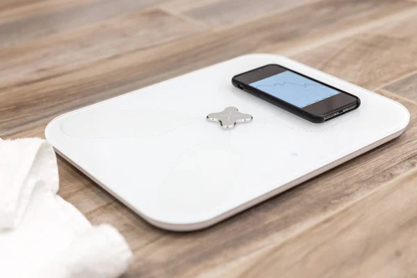 Smart scale standing on floor connected by bluetooth to smartphone — Stock Photo, Image