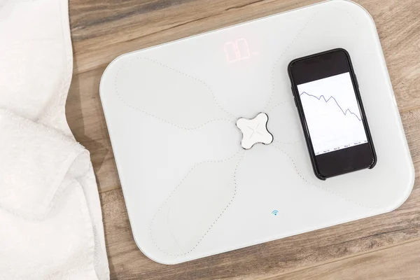 Smart scale standing on floor connected by bluetooth to smartphone