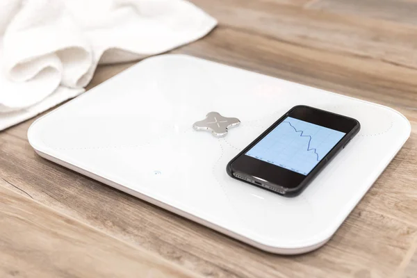 Smart scale standing on floor connected by bluetooth to smartphone