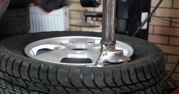 Serviço de pneus Homem colocado no pneu na roda do carro por ferramenta especial — Fotografia de Stock