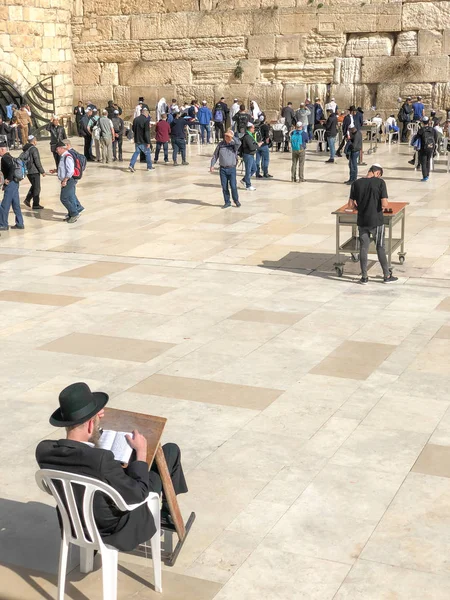 JERUSALEM, ISRAEL - JANUARY 22, 2019: Jewish worshiper prays at the Wailing Wall sitting on a chair. The Western Wall, Wailing Wall or Kotel is located in the Old City of Jerusalem