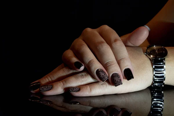 Gorgeous manicure, black color nail polish, closeup photo. Female hands with dark background