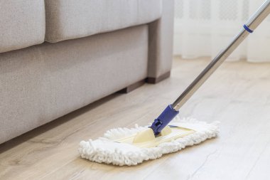 Cleaning floor with white mop near sofa clipart