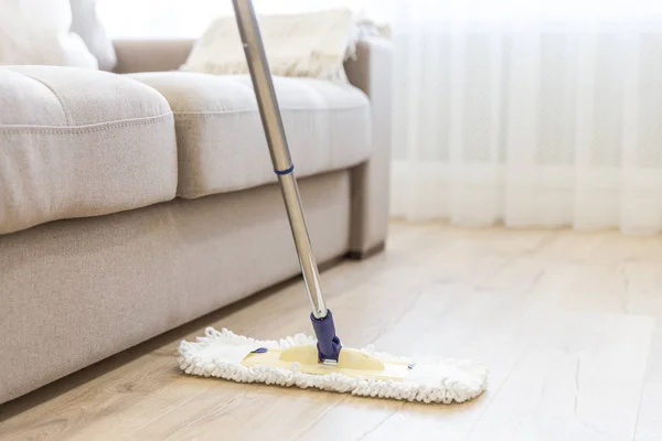 Rengöring av golv med vita mopp nära soffa — Stockfoto