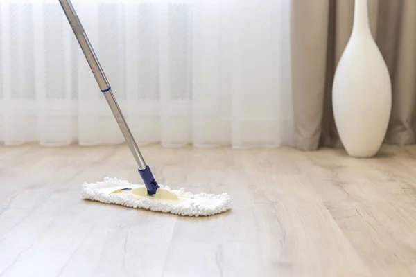 Piso de limpieza con fregona blanca cerca del sofá —  Fotos de Stock