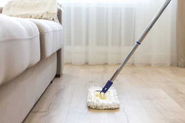 Nettoyage sol avec balai blanc près du canapé — Photo