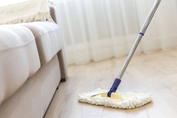 Piso de limpieza con fregona blanca cerca del sofá — Foto de Stock