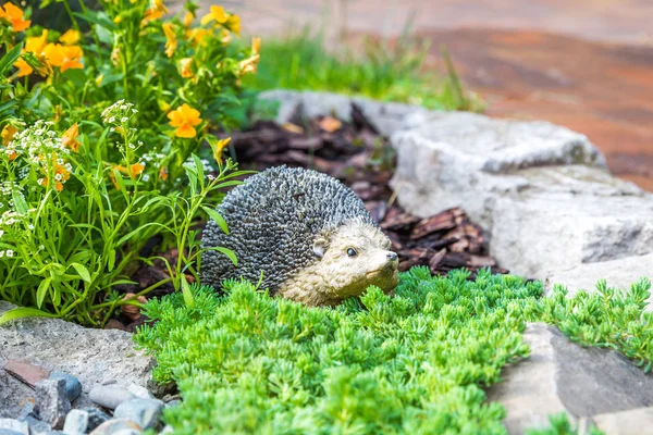 Decorative hedgehog garden decor. Ceramic statue on a flowerbed