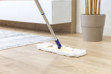Wooden floor with white mop, cleaning service concept clipart