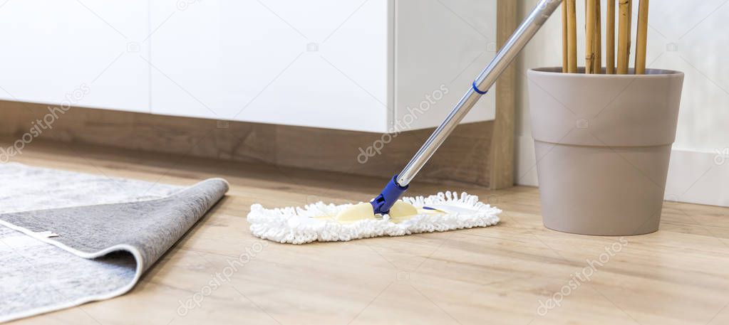 Wooden floor with white mop, cleaning service concept