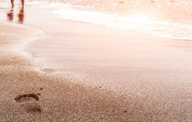 Güneş parlaması ile gün batımı nda plaj, dalga ve kadın ayak izleri