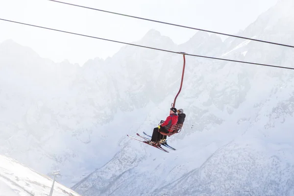 DOMBAI, RUSSIA - JANUARY 3, 2014: People are lifting on open lft high up in Caucasus mountains — Stock Photo, Image