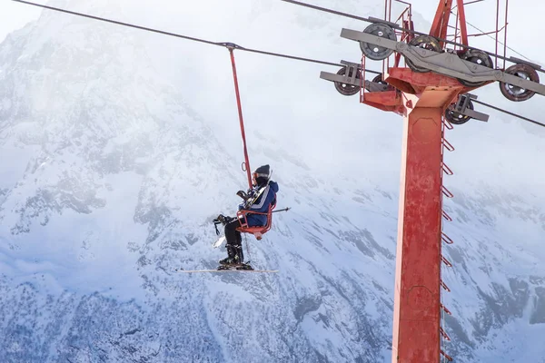 DOMBAI, RUSSIA - JANUARY 3, 2014: People are lifting on open lft high up in Caucasus mountains — Stock Photo, Image