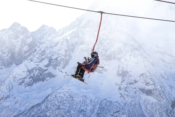 DOMBAI, RUSSIA - JANUARY 3, 2014: People are lifting on open lft high up in Caucasus mountains — Stock Photo, Image