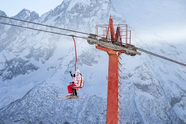 DOMBAI, RUSSIA - JANUARY 3, 2014: People are lifting on open lft high up in Caucasus mountains — Stock Photo, Image