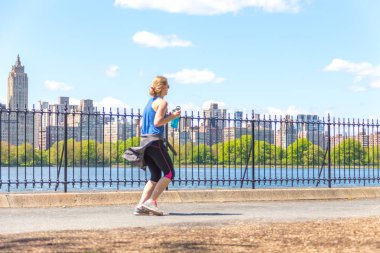New York, ABD-15 Mayıs, 2019: Jogger New York 'ta Central Park rezervuar boyunca çalışan. Central Park, yıl boyunca aktif insanlarla doludur..
