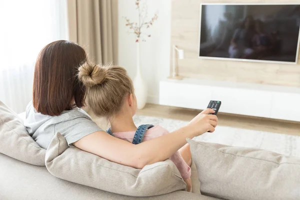 Anne ve kızı kanepede oturarak televizyon izlerken — Stok fotoğraf