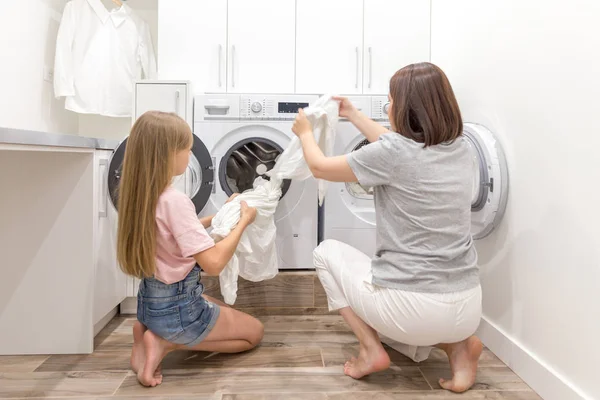 Chica ayudando a su madre en la sala de lavandería — Foto de Stock
