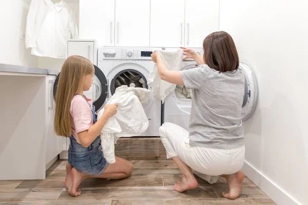 Chica ayudando a su madre en la sala de lavandería — Foto de Stock