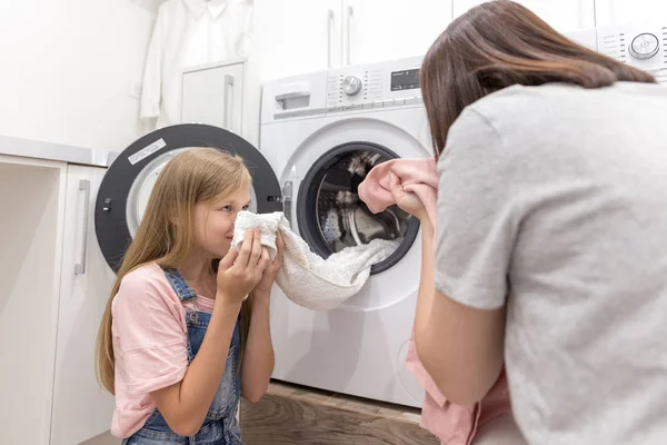 Lycklig familj mor hemmafru och barn dotter i tvättstuga med tvättmaskin och kläder — Stockfoto