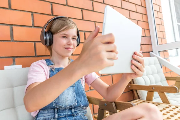 一个年轻的女孩喜欢听她的耳机与平板电脑的音乐 — 图库照片