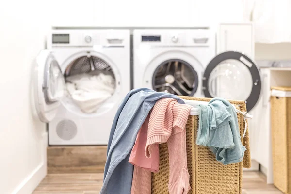 Laundry room with basket and washing and drying machines on background