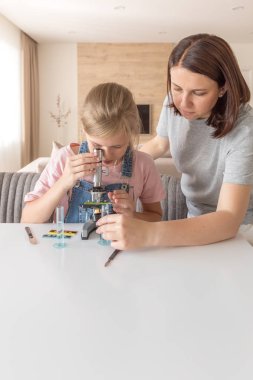 Anne ve kızı evde mikroskop ile kimyasal deneyler yapmak