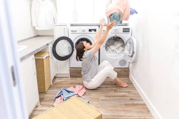 Щаслива родина домогосподарка в пральні з пральною машинкою кидає одяг вгору — стокове фото
