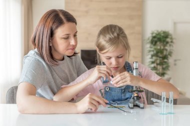 Anne ve genç kızı evde mikroskop ile bazı deneyler yapıyor