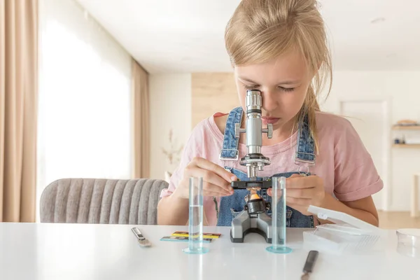 Girl with microscope at home learning chemistry and playing — Stock Photo, Image