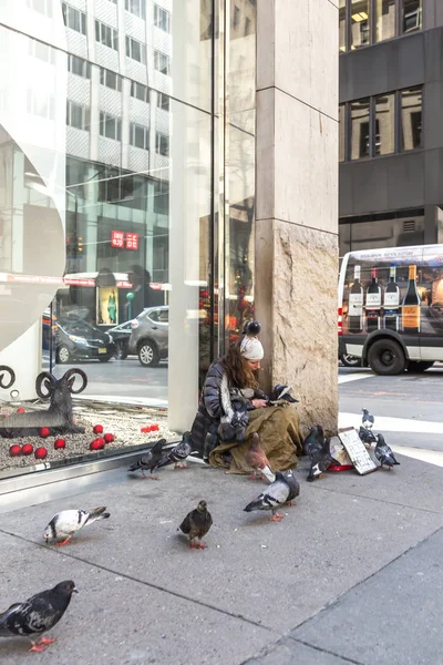 NEW YORK CITY, NEW YORK, USA - MAY 15, 2019: Young homeless woman with many doves looking for charity from passers by on 5th avenue in New York — Stock Photo, Image