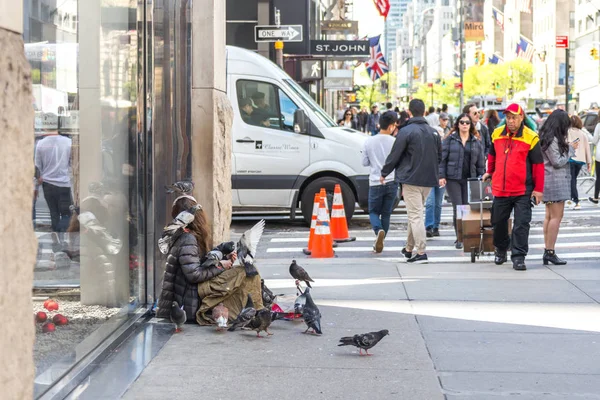 NEW YORK CITY, NEW YORK, USA - MAY 15, 2019: Young homeless woman with many doves looking for charity from passers by on 5th avenue in New York — Stock Photo, Image