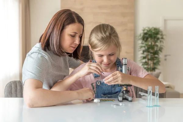 母亲和小女儿在家里用显微镜做实验 — 图库照片