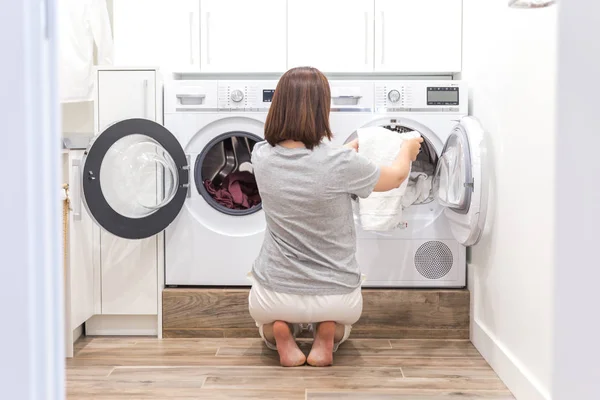 Mujer poniendo ropa a la lavadora para lavar — Foto de Stock