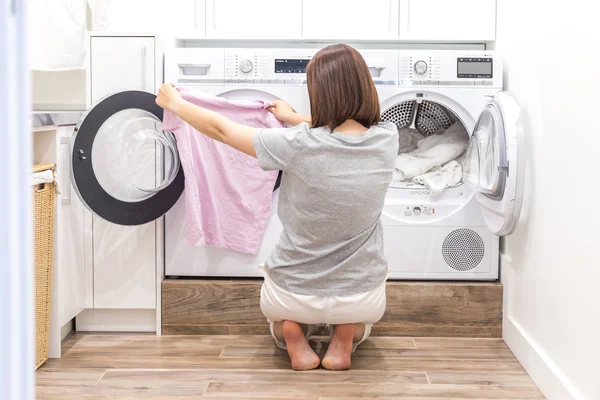 Mujer poniendo ropa a la lavadora para lavar — Foto de Stock