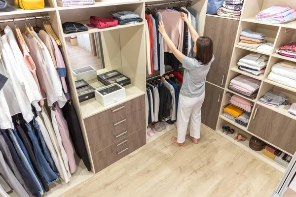 Hermosa chica está eligiendo ropa en su vestidor — Foto de Stock