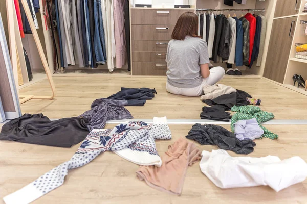 Mujer joven tirando ropa en el armario. Desorden en armario y vestidor —  Fotos de Stock